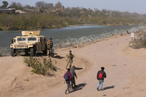 A group of migrants from Venezuela walk along the banks of the Rio Grande to surrender to U.S. Border Patrol after they entered Eagle Pass, Texas, Monday, Jan. 8, 2024. (Jay Janner/Austin American-Statesman via AP)