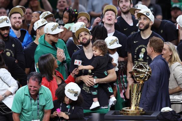 Derrick White of the Celtics holds his son Hendrix James while being interviewed by ESPN's Lisa Salters after Boston's NBA champio<em></em>nship win on June 17, 2024.