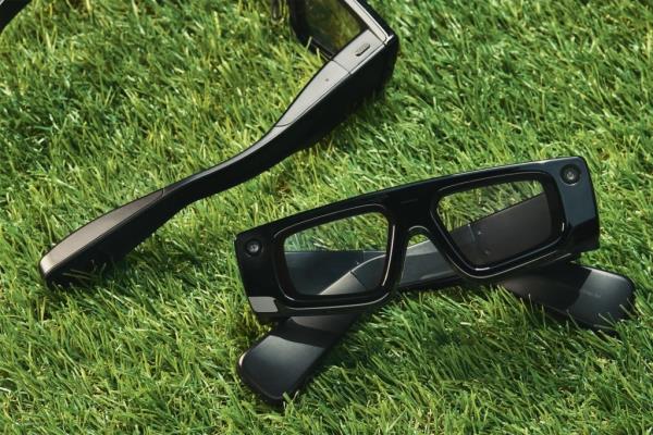 Black smart glasses resting on grass.